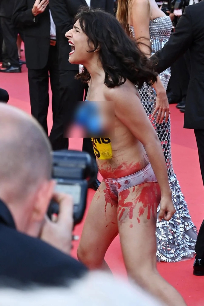 Nude protester with 'Stop Raping Us' painted on chest interrupts red carpet at Cannes Film Festival