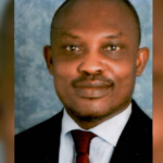 Man in formal attire, neutral background.