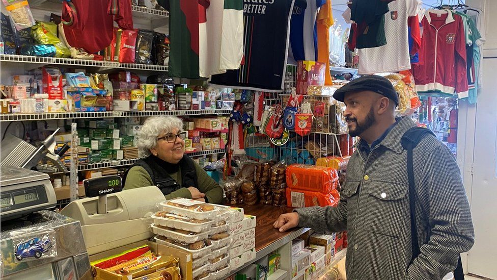 Challenger John Gomes speaks with a shopkeeper in Bridgeport