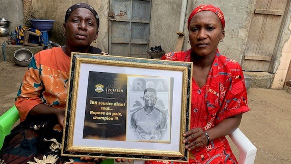 The mother and sister of Moustapha Sylla hold a pictorial tribute to the deceased Ivorian footballer