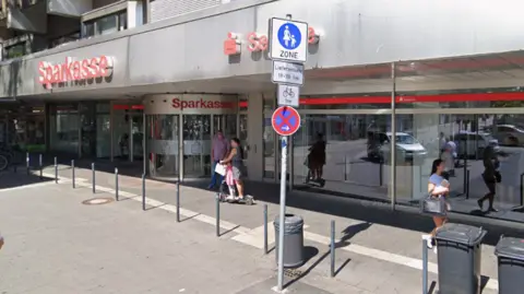 Google A Google streetview shot shows the silver and red facade of the Sparkasse branch on a high street. People can be seen walking past its windows